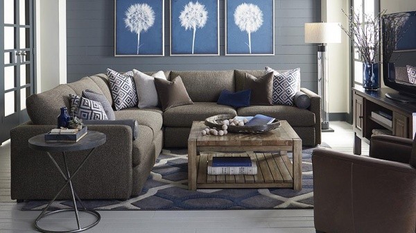 luxury living room with a blue color scheme including a brown couch with pillows, a wooden table, and brown leather chair