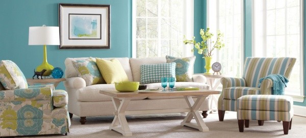 luxury living room featuring cyan, white and olive color scheme with cream colored sofa with multi colored pillows and multiple cyan white and olive chairs